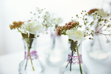 Mini glass vases with flowers on table