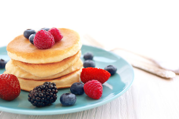 Plate with delicious pancakes and berries on table, closeup