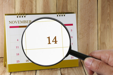 Magnifying glass in hand on calendar you can look fourteenth day