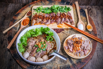 Thai noodle soup with sliced beef and beef meatballs on big wood cutting board