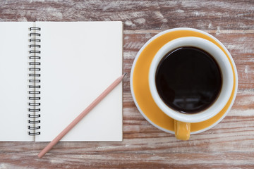 Notepad and coffee cup on wood table. View from above