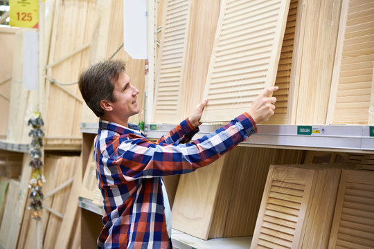 Man chooses wooden facades for furniture in store