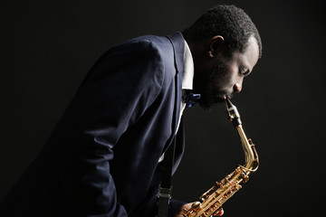Naklejka premium African American jazz musician playing the saxophone on grey background