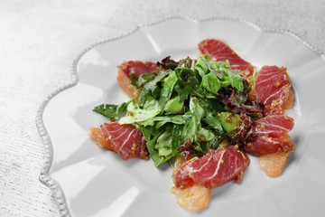Plate with fish salad on white wooden background