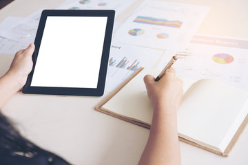 working, tablet on hand, white background on tablet, writing on note book.