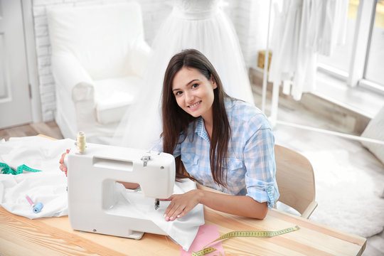 Pretty young dressmaker with sewing machine