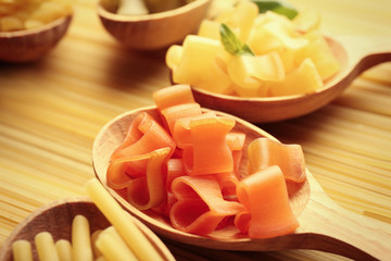 Different dry pasta on wooden spoons, close up