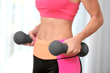 Sporty young woman doing exercises with dumbbells