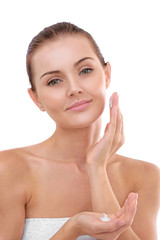 Portrait of beautiful young woman in white towel applying cream onto face