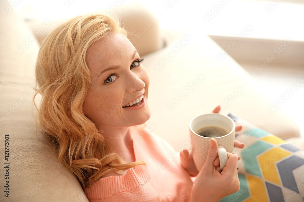 Poster beautiful girl drinking coffee on couch