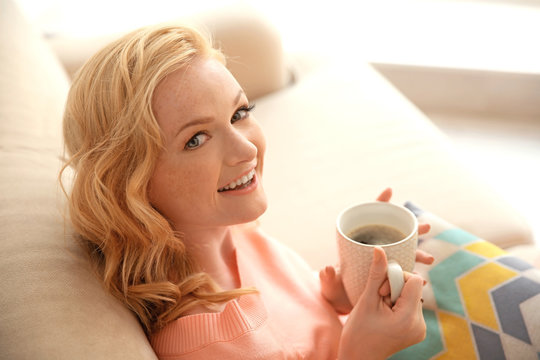 Beautiful girl drinking coffee on couch