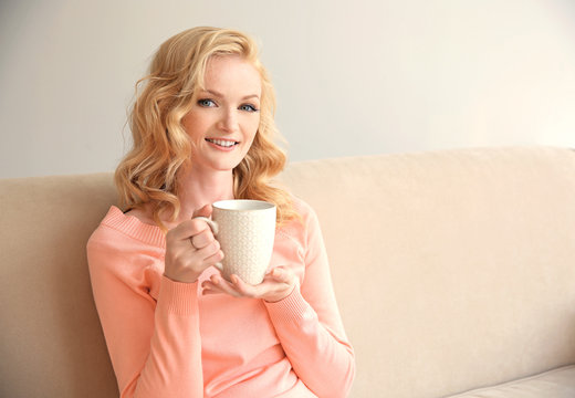 Beautiful girl drinking coffee on couch