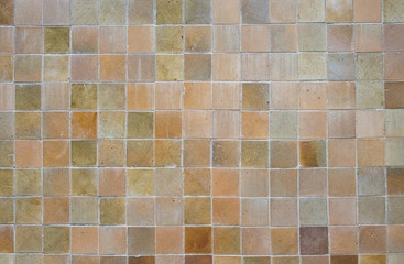 the old, dirty, alkali, rust dark orange and red chipped wall tiles of the building background texture