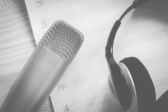 studio condenser microphone & headphone on blank music sheet