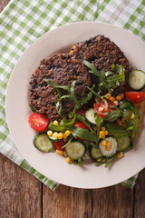 Vegetarian black bean burgers and fresh vegetable salad closeup. Vertical top view
