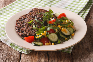 Vegan black bean burgers and fresh vegetable salad close-up on a plate. horizontal

