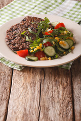 Vegetarian black bean burgers and fresh vegetable salad close-up on the table. Vertical
