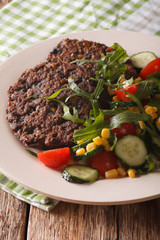 Vegetarian black bean burgers and a salad of fresh vegetables close-up. vertical
