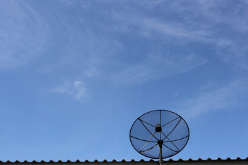 Black Satellite dish on roof in blue sky background.