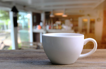 White Coffee cup on wooden table in coffee shop blur background.