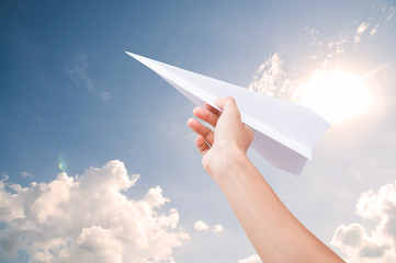 Hand holding paper plane toward cloudy blue sky concept new innovation and new creativity.