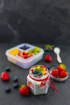 Healthy breakfast in lunch box. Yogurt with fresh berries fruit and chia seeds on stone background.