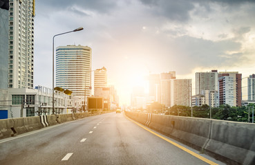 Urban road with skyscraper at sunset shining