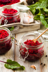 Grated beetroot marinated in jars. Wooden background.