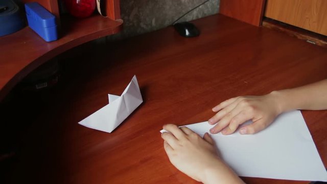 children's hands making origami plane