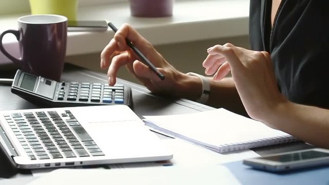 Close up of female accountant or banker making calculations. Home finances, investment, economy, saving money or insurance concept. Hands closeup.