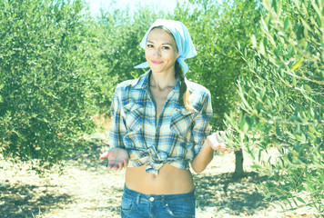 Young smiling woman gardener standing among olive trees