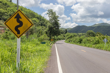 Winding road sign with mountain and sky in thailand