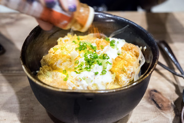 Omelet top pork crispy and rice in bowl black with pour chili