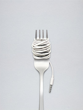 Naklejki Food for new generation / A shining fork with noodle made of cable with music jack plug in metal background.