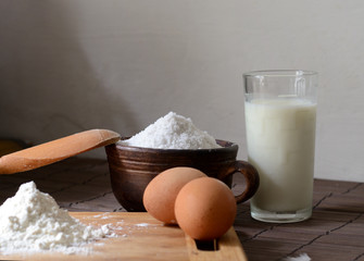 Ingredients for homemade bread or pasta. Eggs, milk, flour on a rustic table. Backing background.