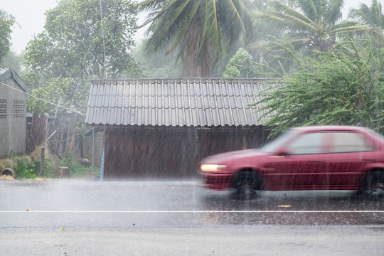 Car driving motion through gale rain on front wooden house in ru