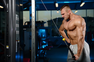 Fototapeta na wymiar Handsome muscular bodybuilder man doing exercises in gym.