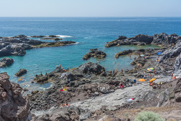 Fototapeta na wymiar An improvised beach on the volcanic lava in Puerto de Santiago.