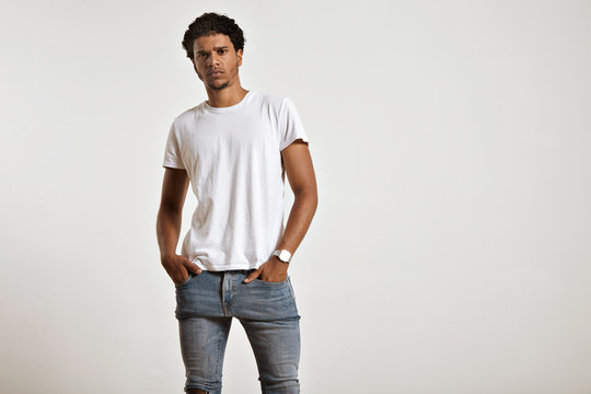 Serious athletic young African American model with hands in the pockets of his tight blue jeans wearing a white t-shirt