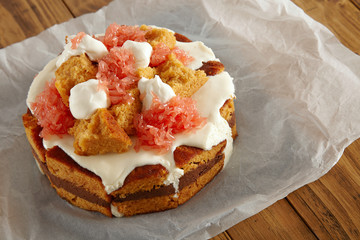 Moist brown cake soaked with cream and chocolate and decorated with grapefruit on a piece of parchment paper