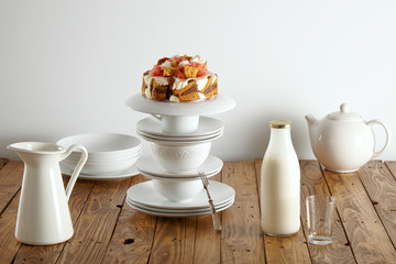 Delicate white tea set, milk bottle and mouthwatering sponge cake with chocolate, cream and grapefruits