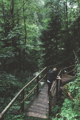 Man with black jacket on a wood bridge in the forest in Austria - 121796115