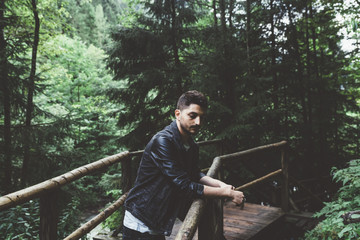 Man with black jacket on a wood bridge in the forest in Austria - 121796500