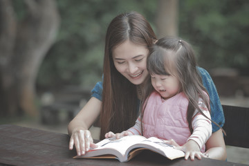 young mother reading a book to her cute daughter vintage style