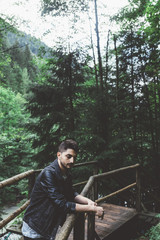 Man with black jacket on a wood bridge in the forest in Austria - 121796700