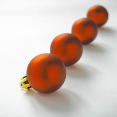 Row of four red decorative christmas balls against white background