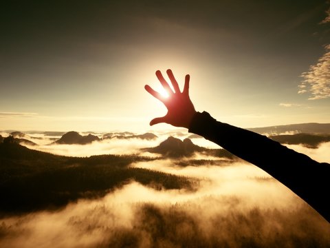 Man hand touch Sun. Misty daybreak in a beautiful hills. Hilly landscape in fog