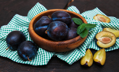 Bowl with  plums with green leaves