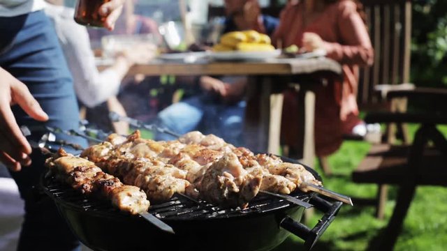 man cooking meat on barbecue grill at summer party