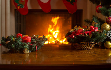 Table with Christmas wreath in front of burning fireplace and de